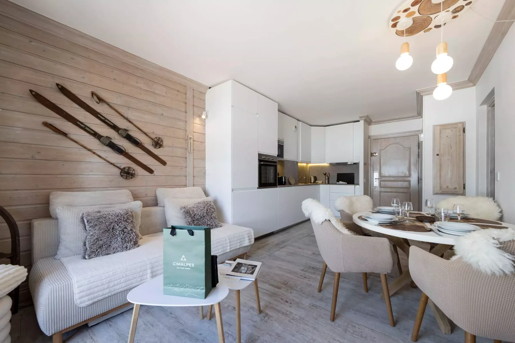 Una sala de estar y comedor integrados con una cocina compacta y asientos claros.
