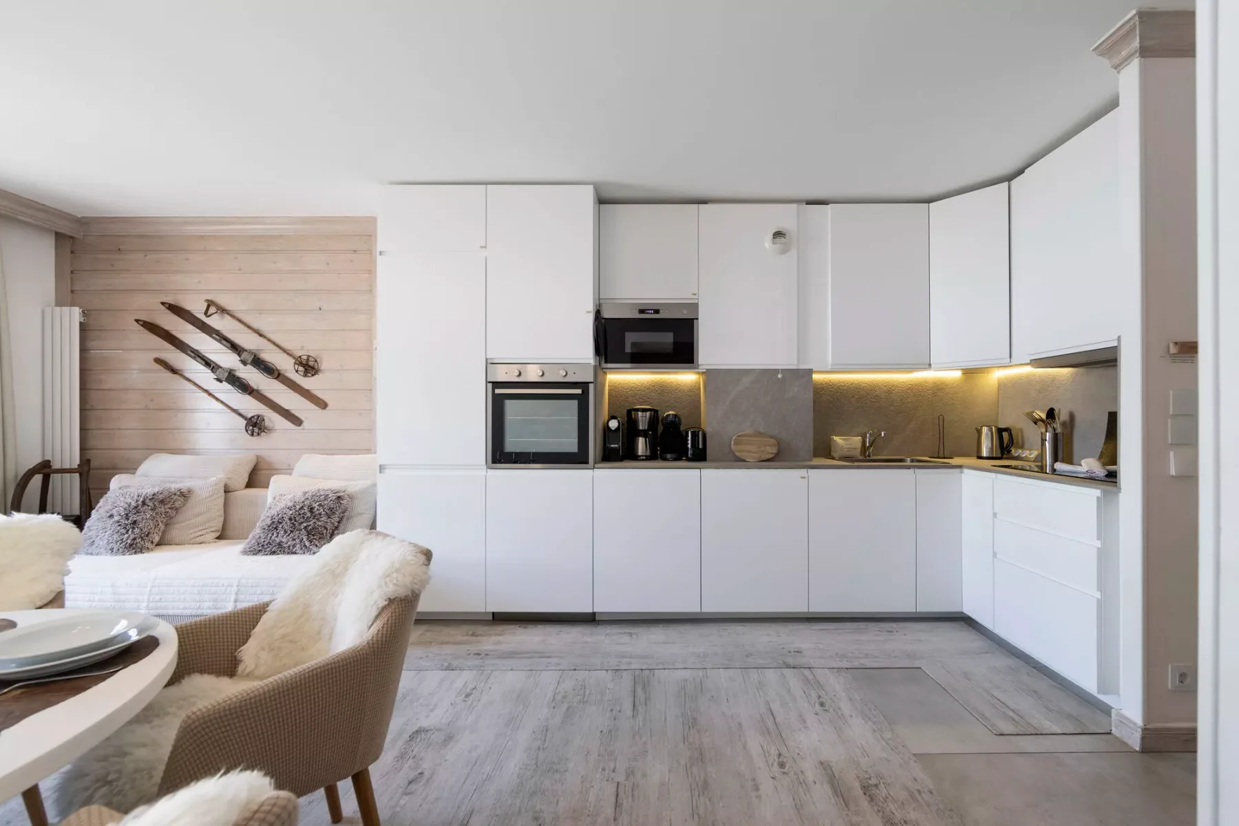 Una cocina abierta y luminosa con gabinetes blancos y una zona de estar.