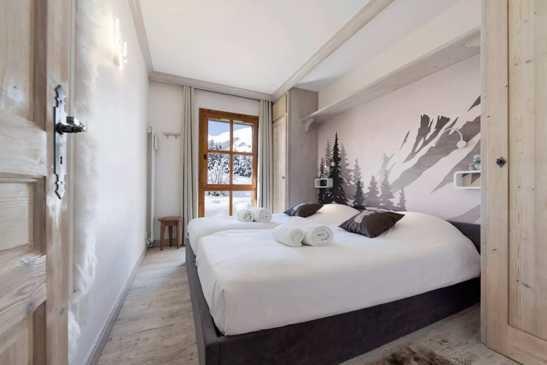 Un dormitorio con una cama grande y un mural de montaña en la pared.
