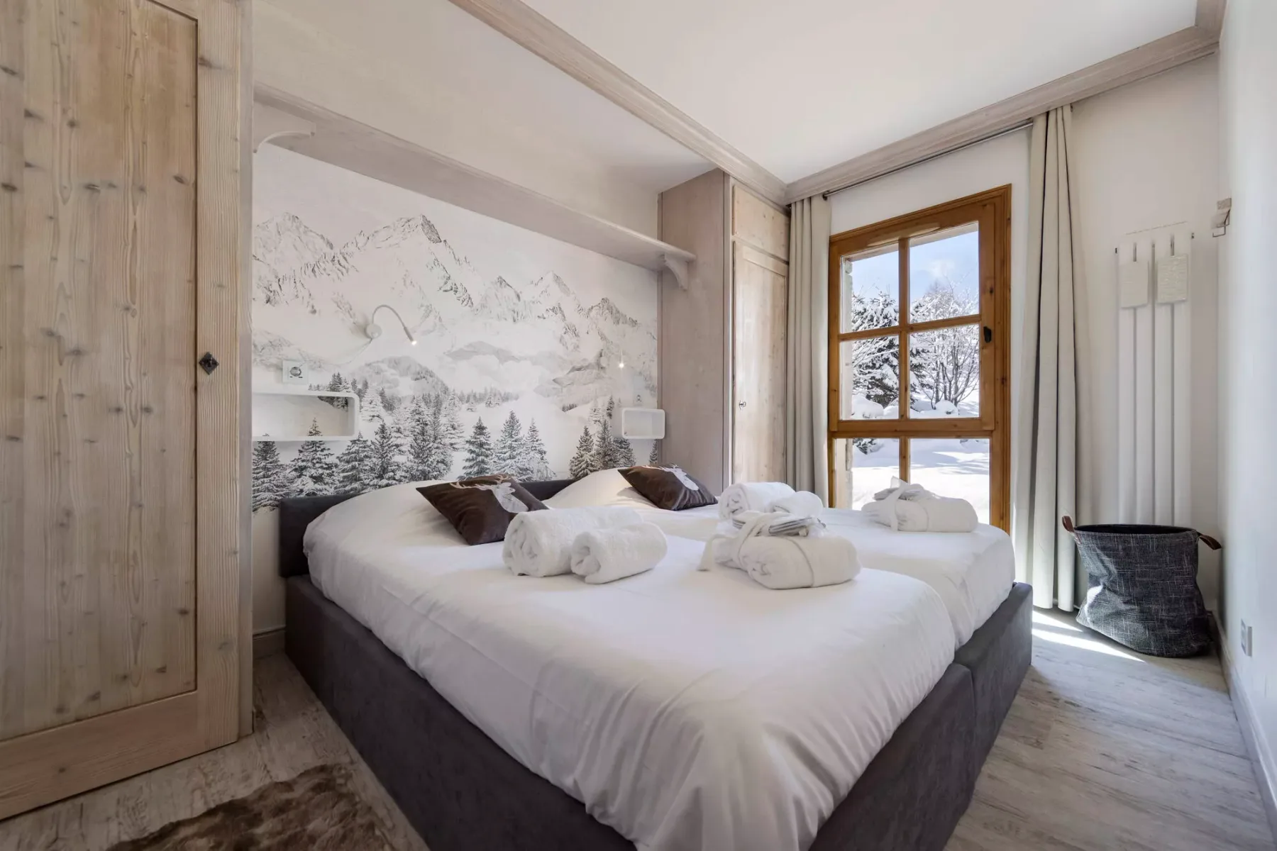 Un dormitorio con una cama grande y un mural de montaña detrás.