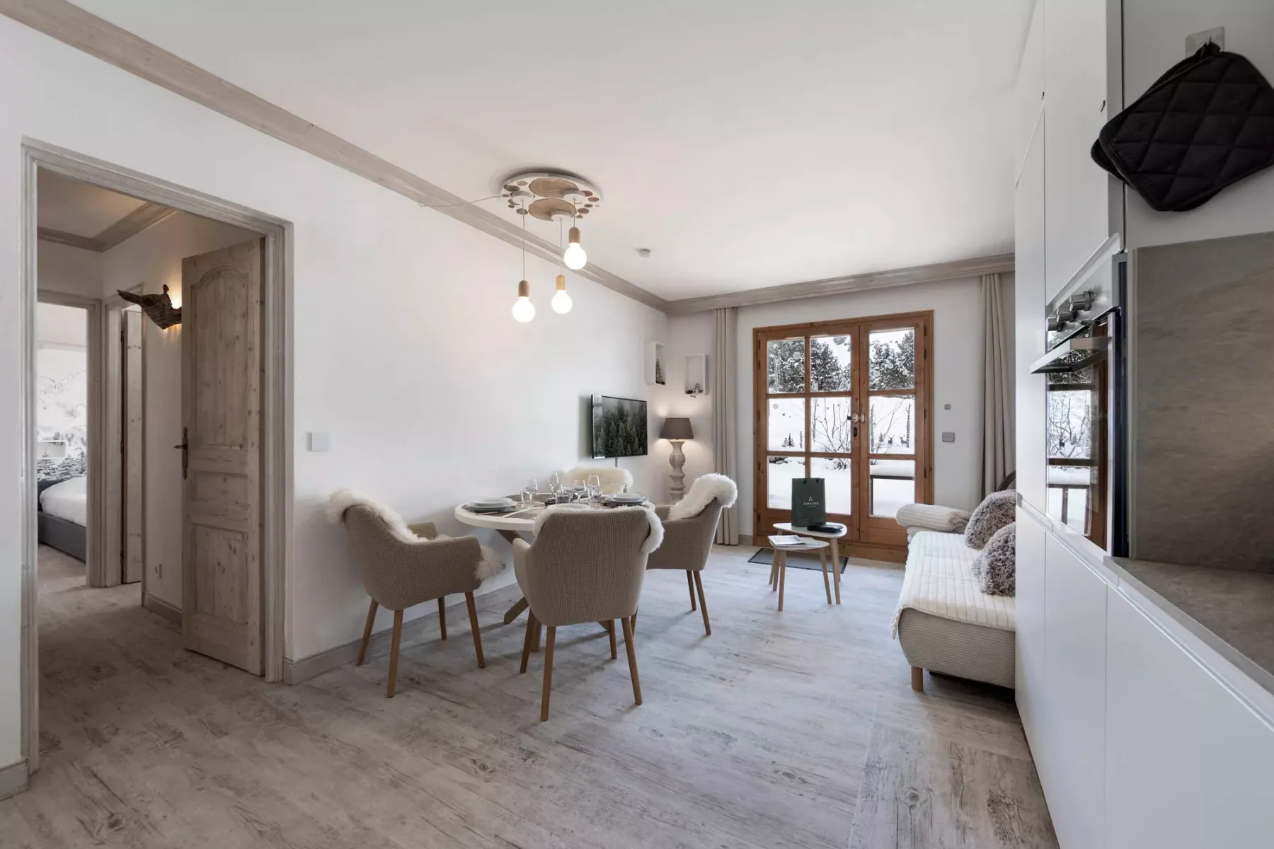 Una luminosa sala de estar y comedor con asientos alrededor de una mesa y puertas acristaladas.