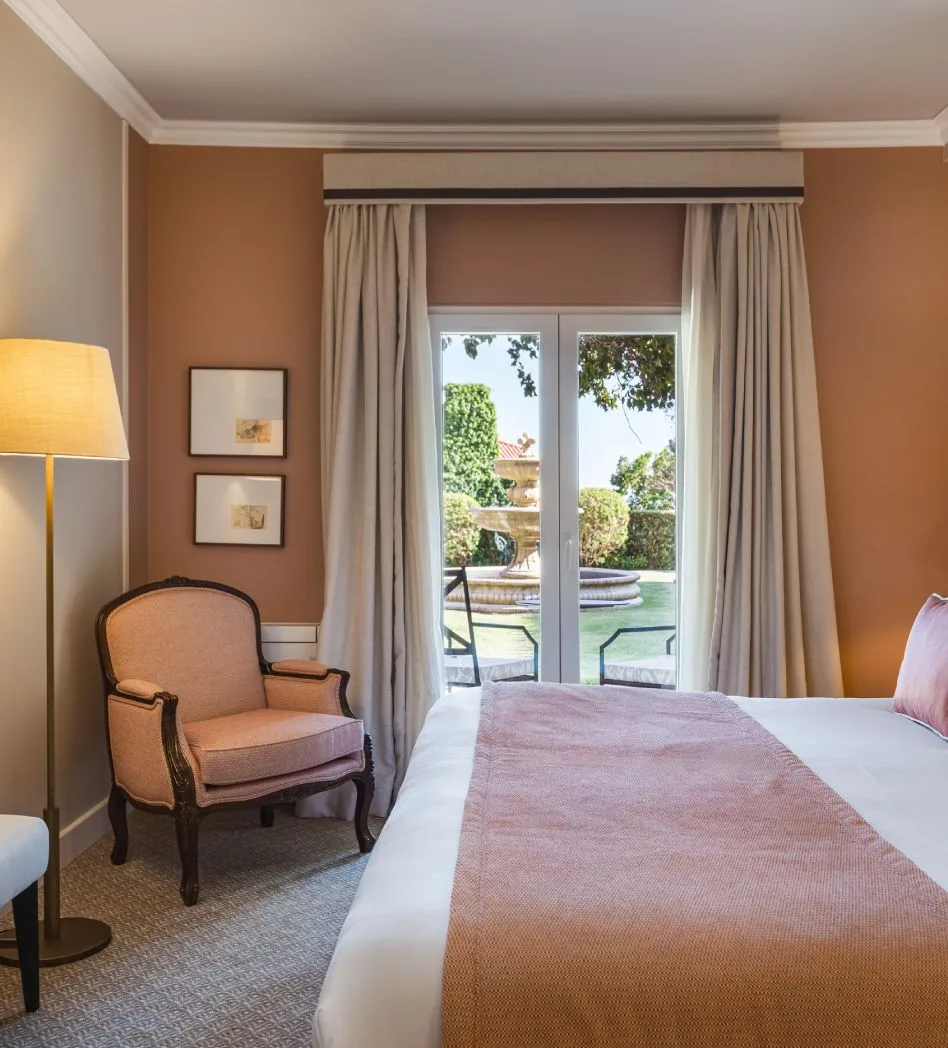 Bedroom with a peach armchair and a garden view.