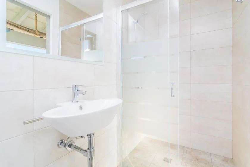 A bright tiled bathroom with a wall-mounted sink and shower.