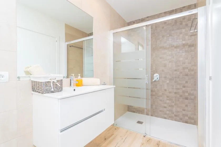 A bright bathroom with a vanity beside a glass shower.
