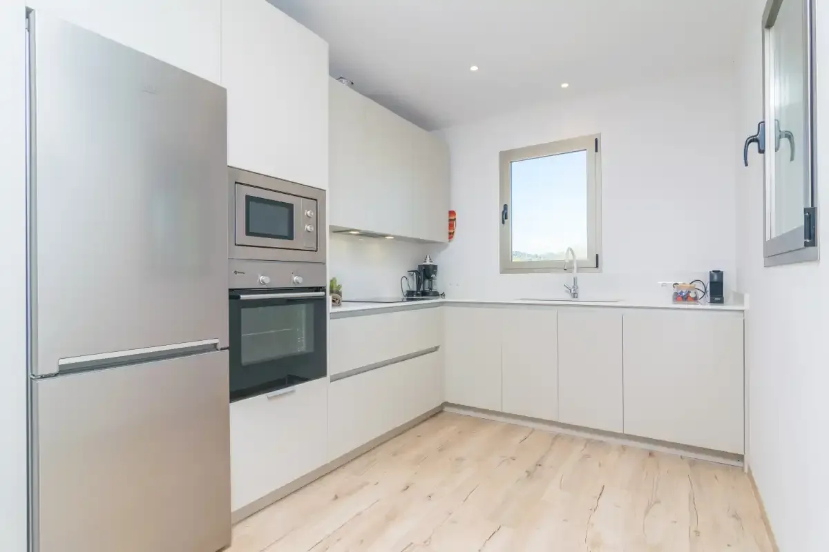 A bright modern kitchen with white cabinetry and a window above the sink.