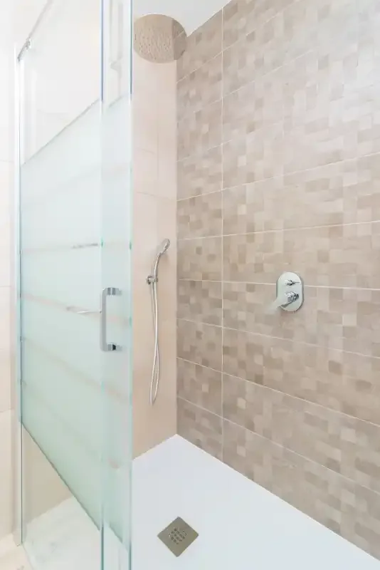 A tiled shower with a glass screen and wall-mounted fixtures.