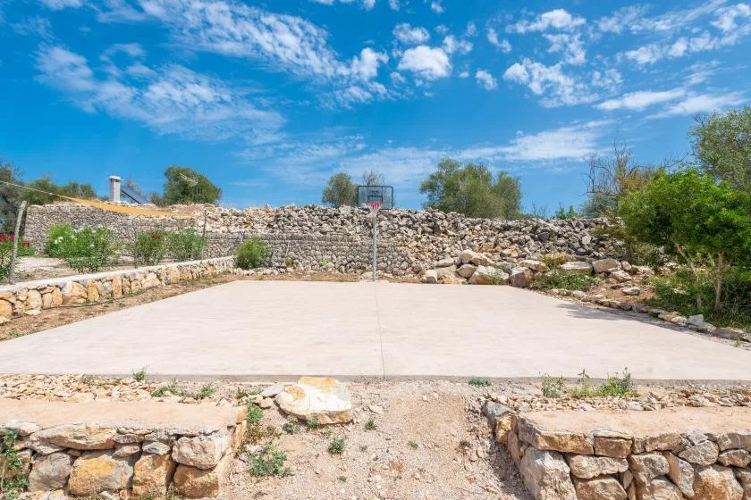 A broad paved outdoor area bordered by low stone walls and greenery.