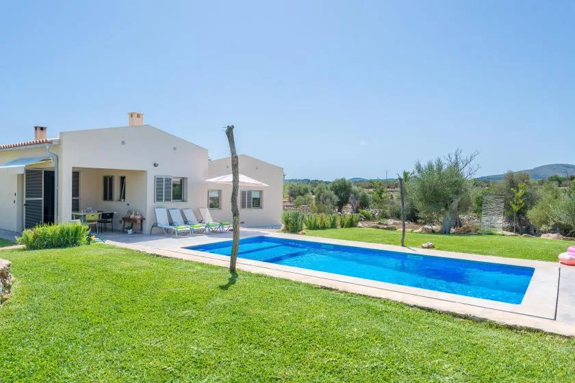 A house and outdoor swimming pool are surrounded by a lawn and garden.