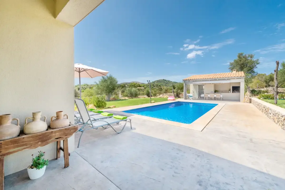 An outdoor pool beside a paved patio and shaded seating area.