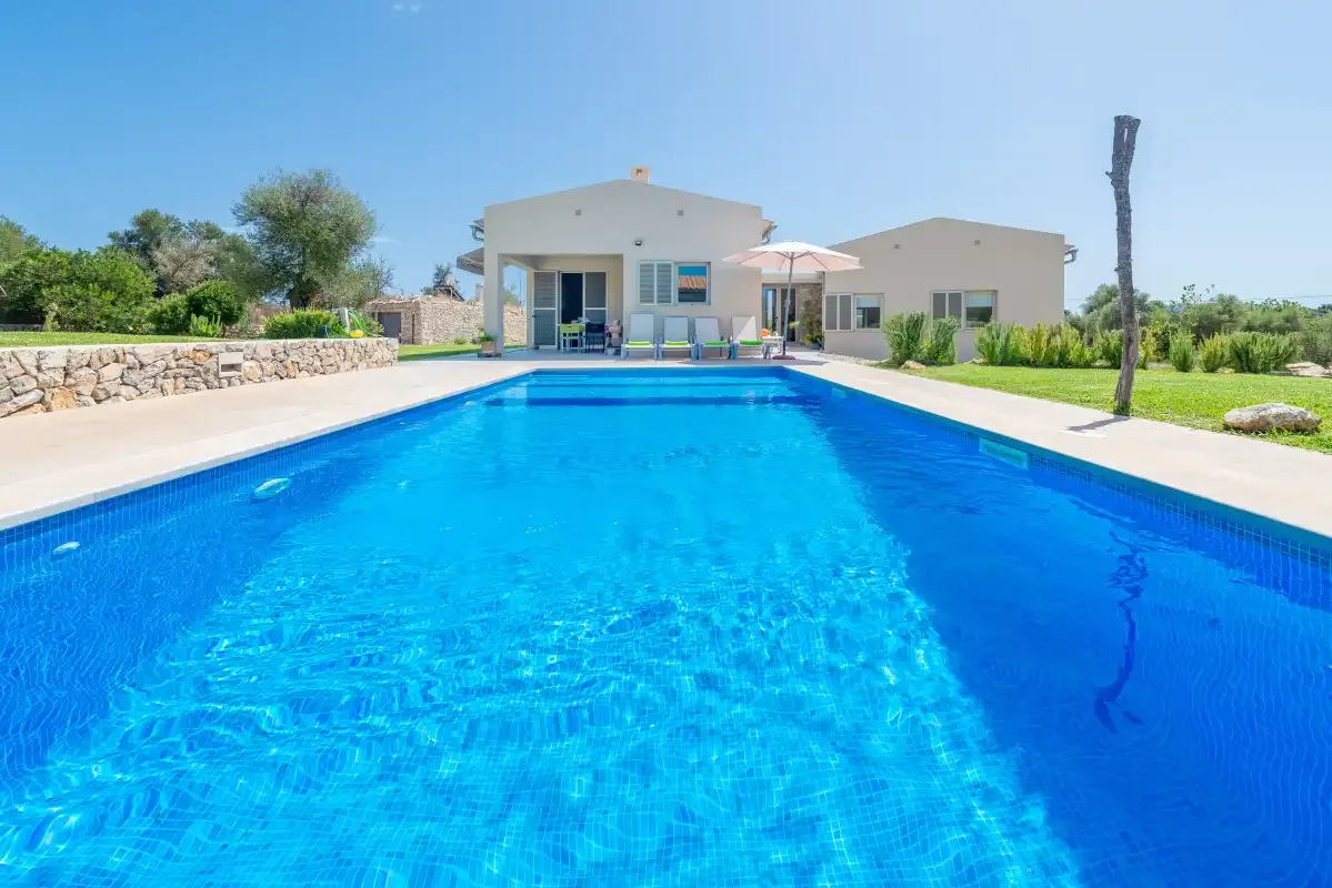 A swimming pool beside a modern house under a clear sky.