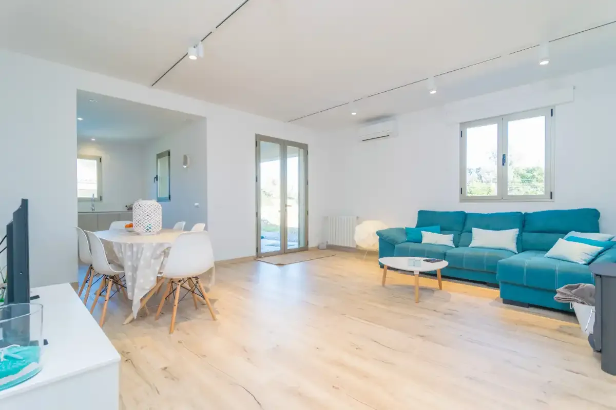 A bright living room with a teal sectional and a dining area.