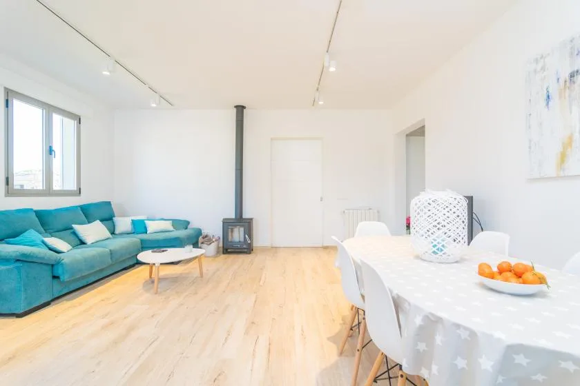 A bright living and dining area with turquoise seating and a table.