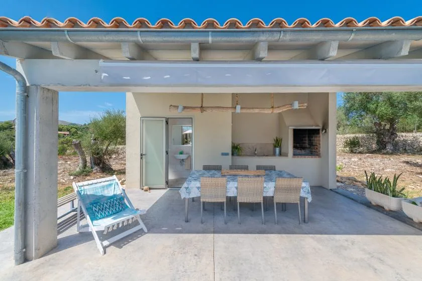 A covered outdoor dining area with a table, seating, and an outdoor kitchen.