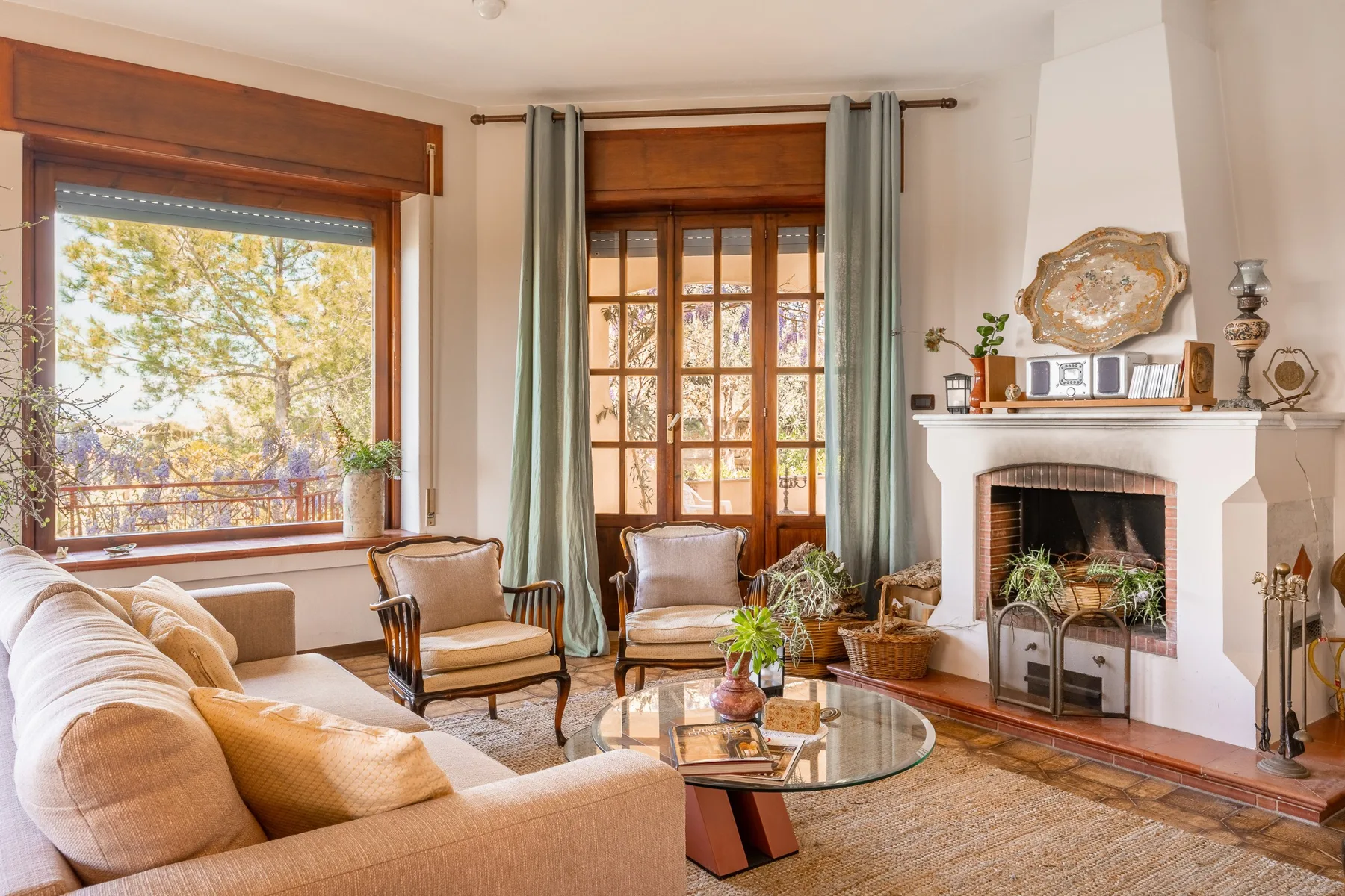 A bright living room with seating, large windows, and a fireplace.