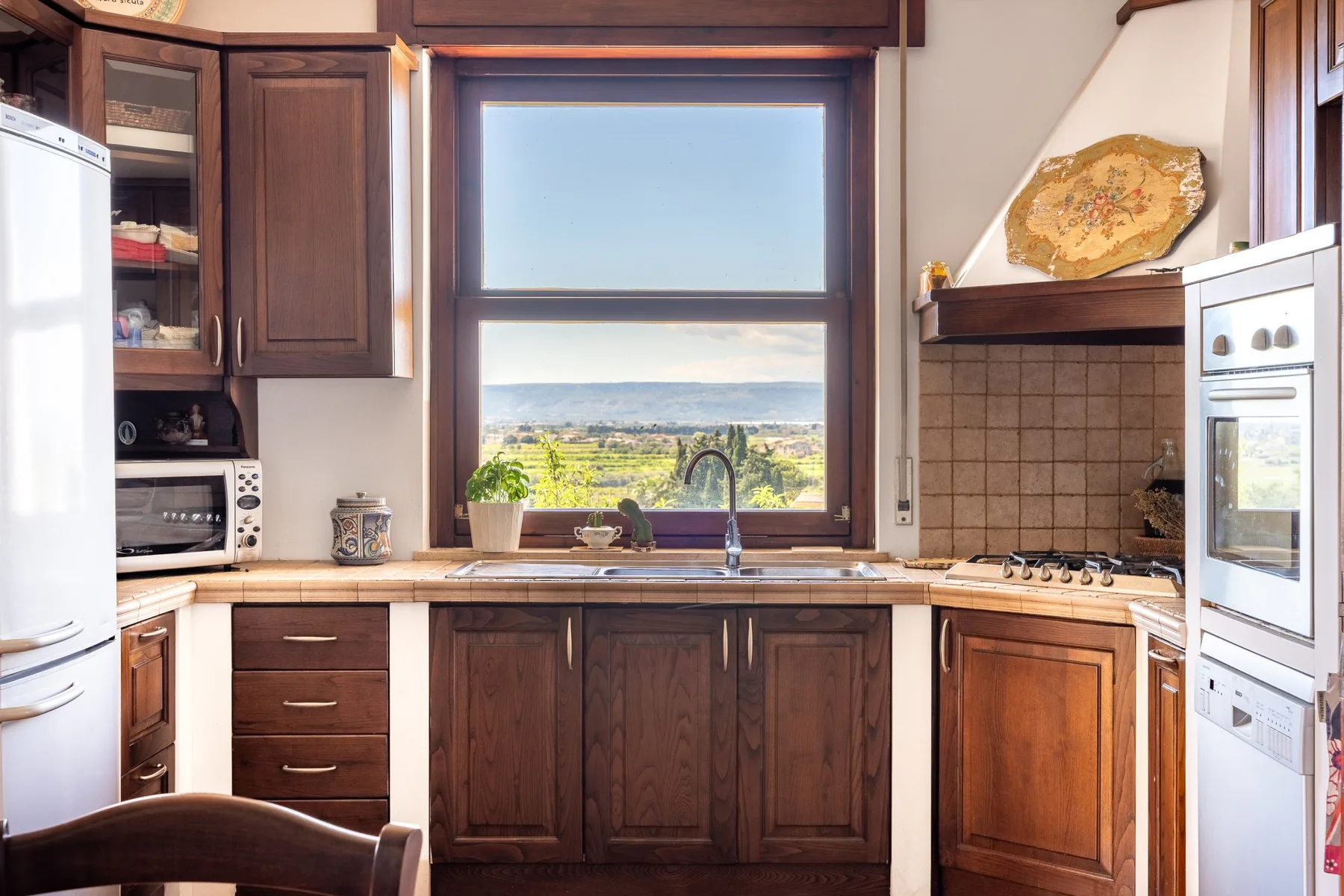 Una cocina con gabinetes de madera oscura, una ventana central y un fregadero.