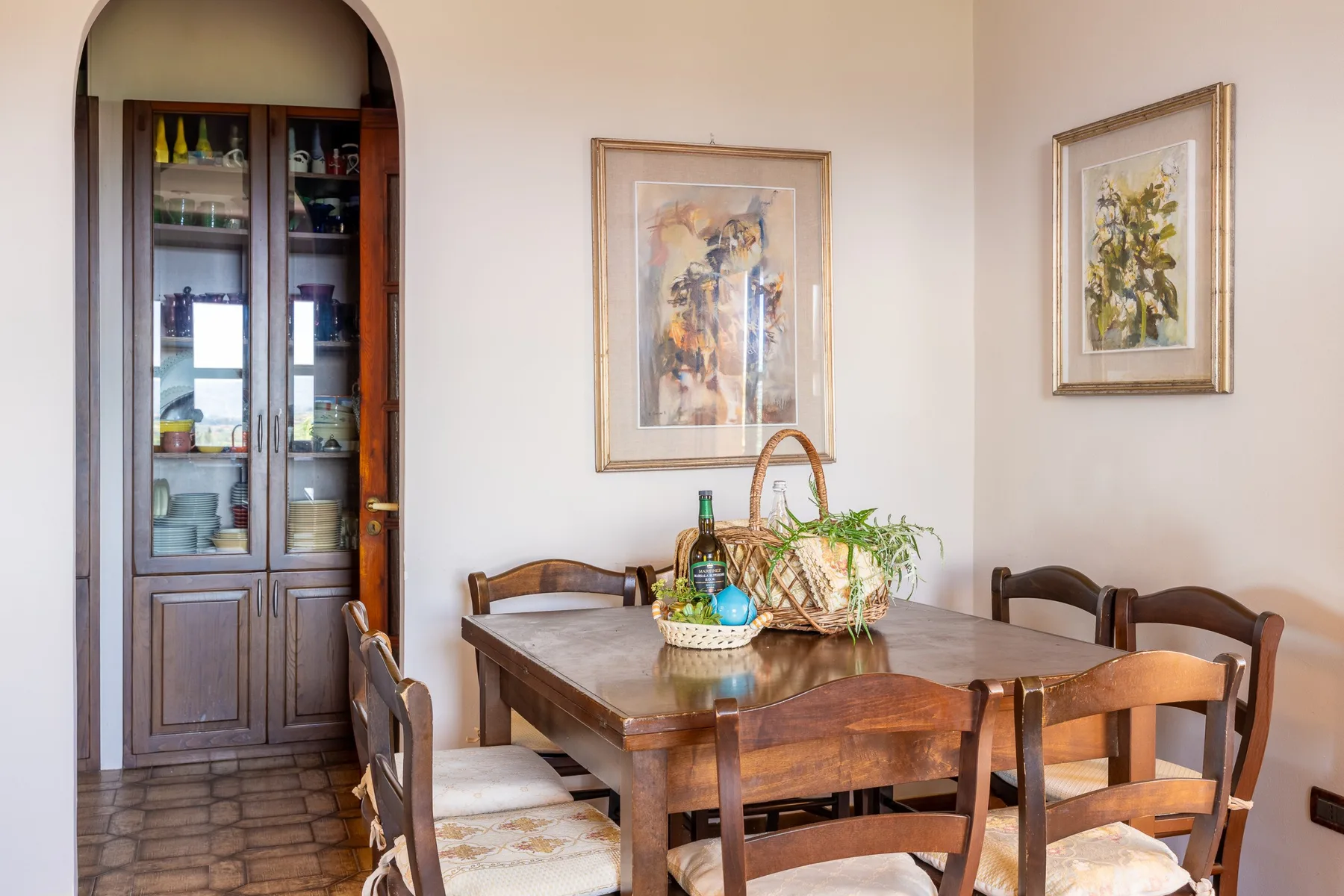 A dining room with a wooden table, chairs, and framed artwork.