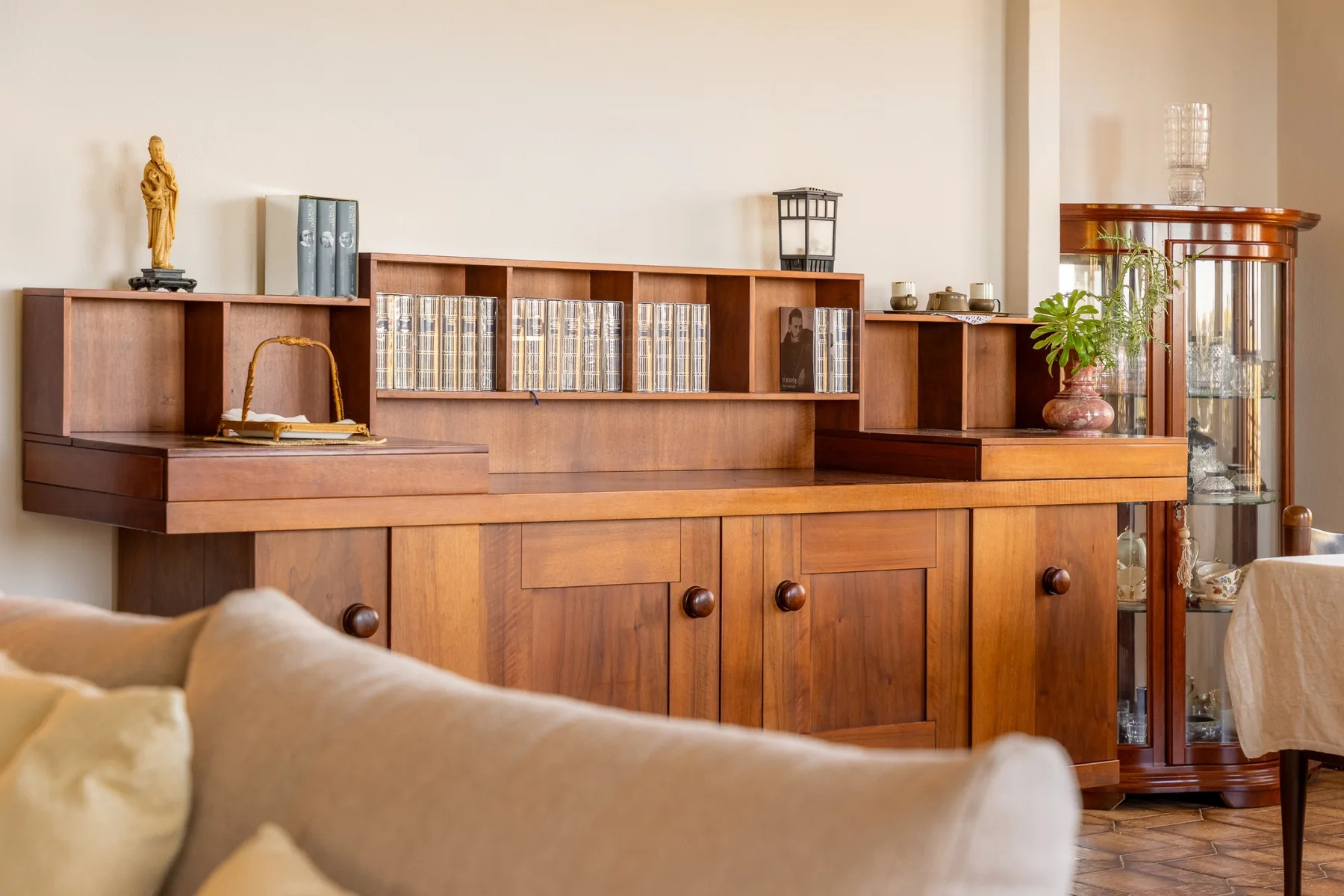 A living room with wooden cabinetry, books, and upholstered seating.