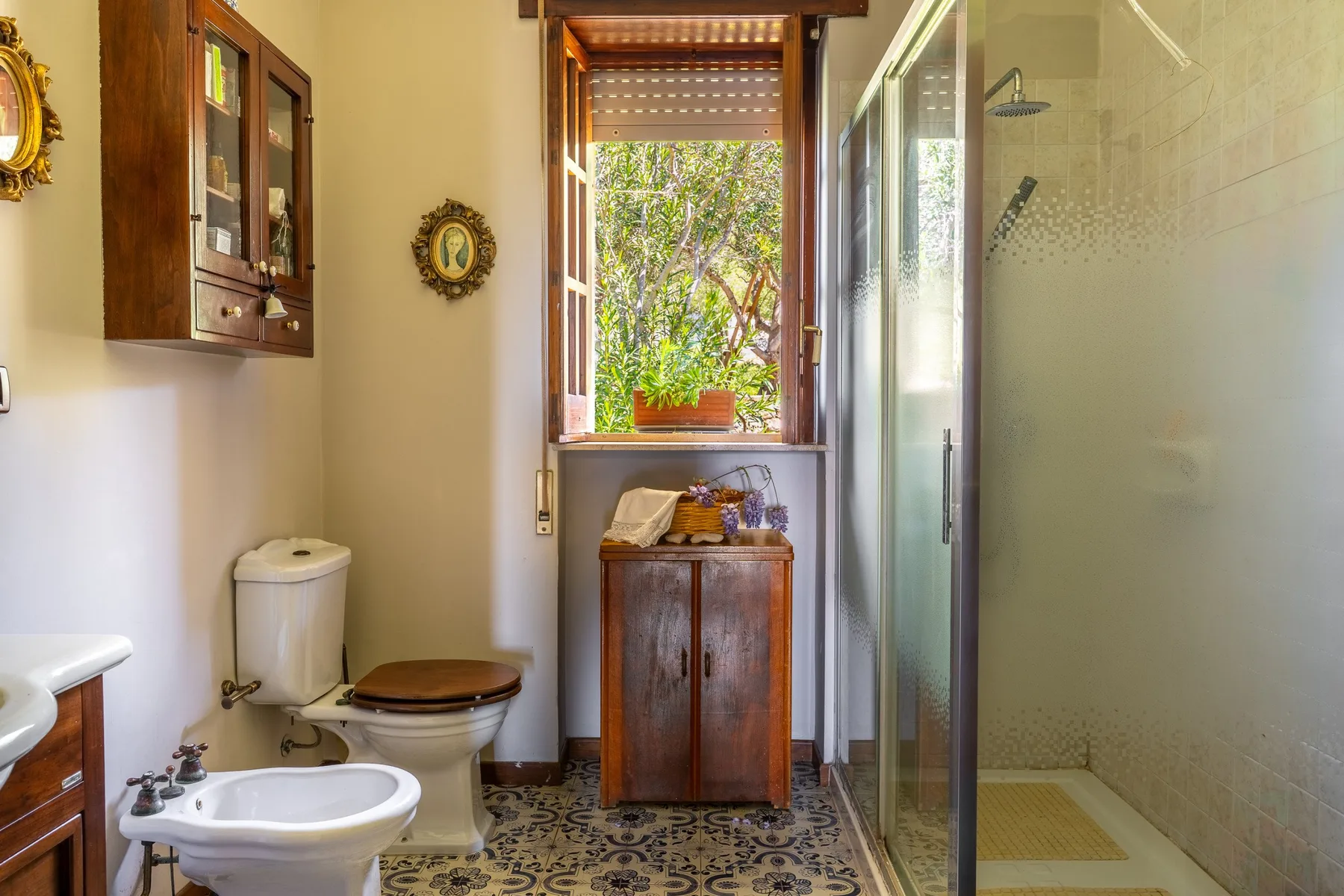 A bathroom with a glass shower, toilet, and patterned floor.