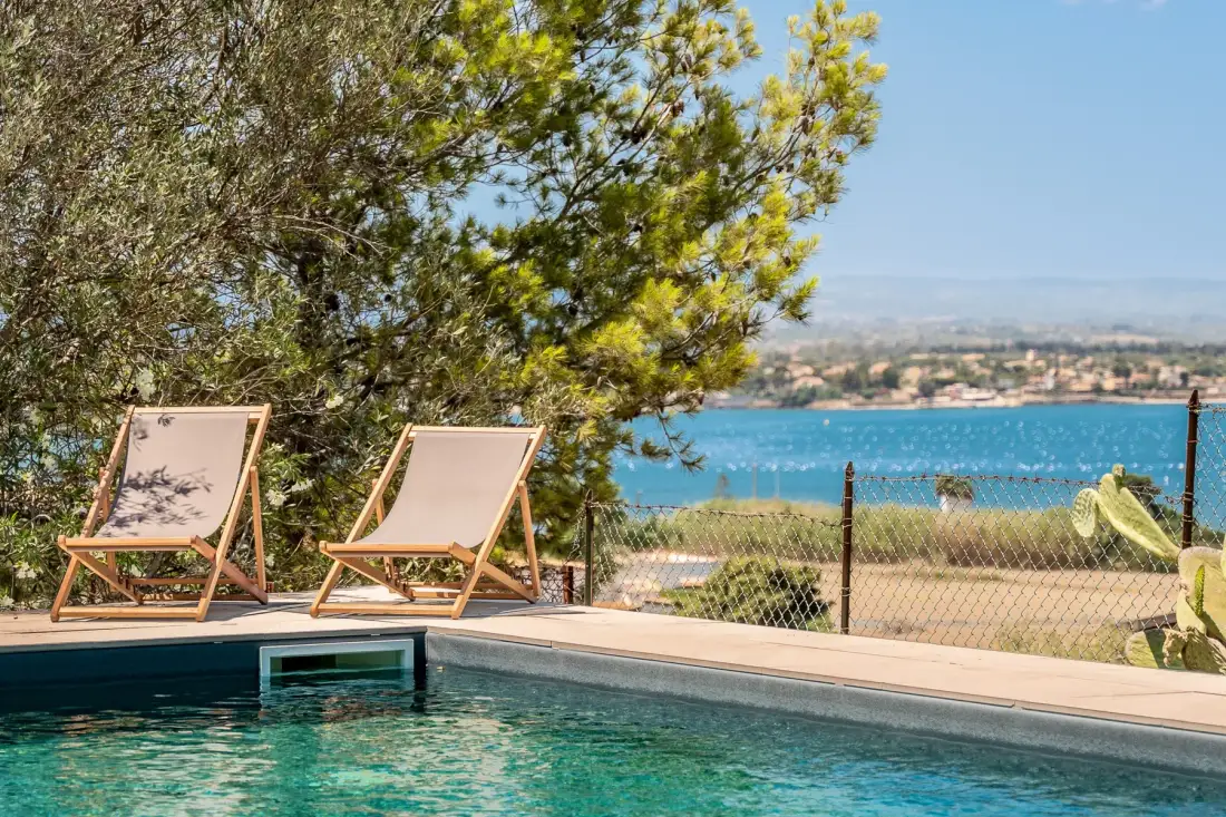 An outdoor poolside area with lounge seating overlooks the water.