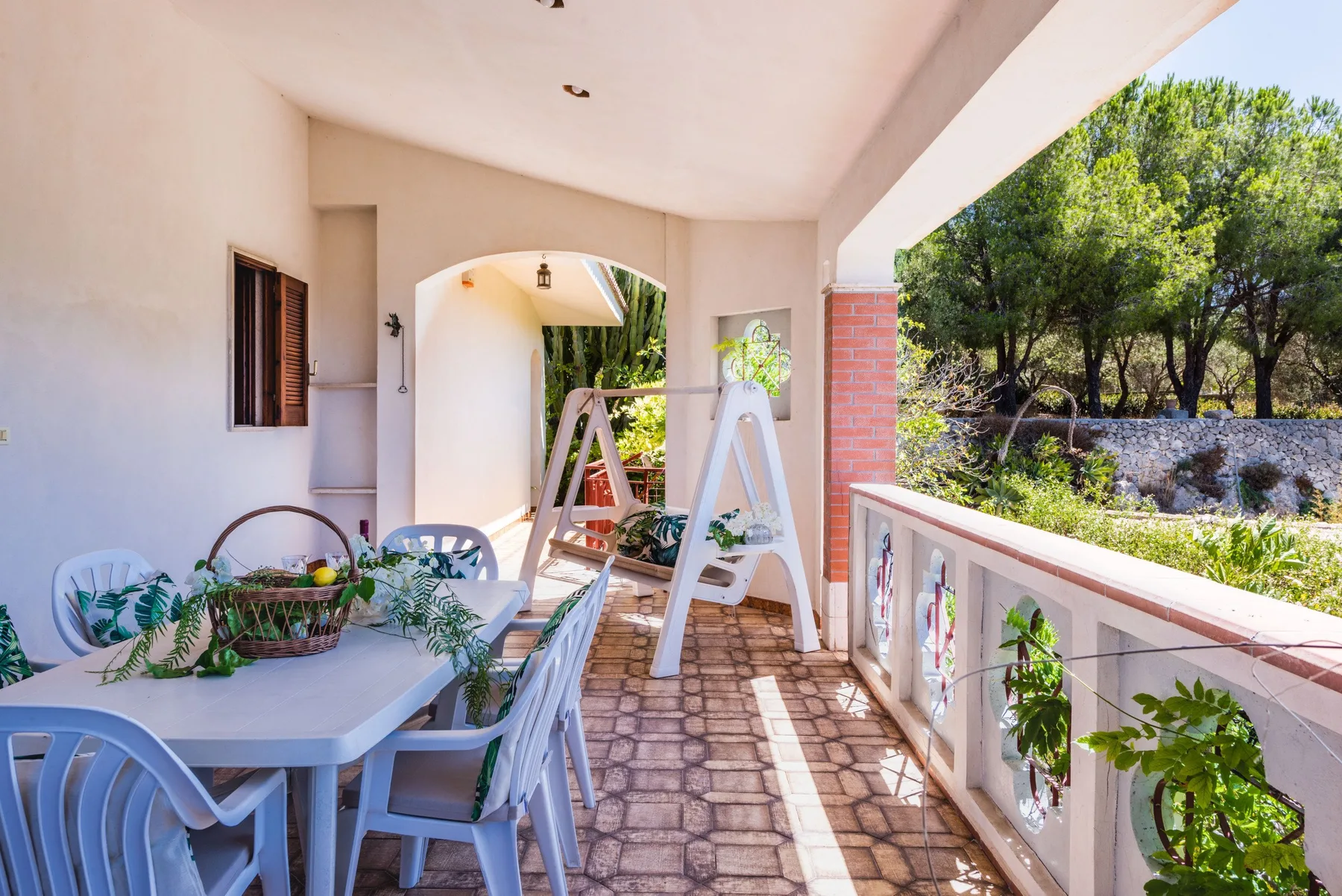 A covered patio with outdoor seating and a garden view.