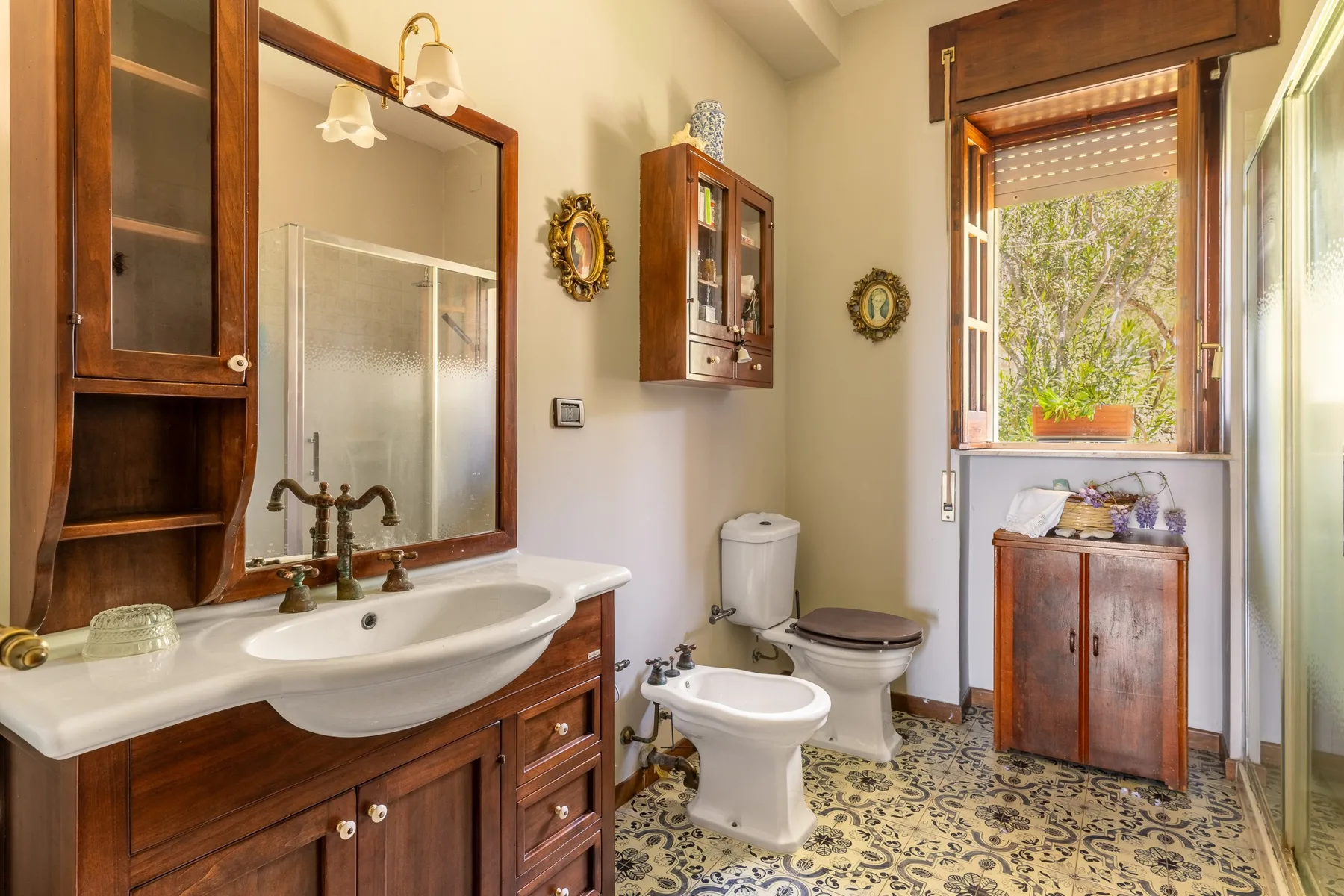 A bathroom with a vanity, toilet, and patterned floor tiles.