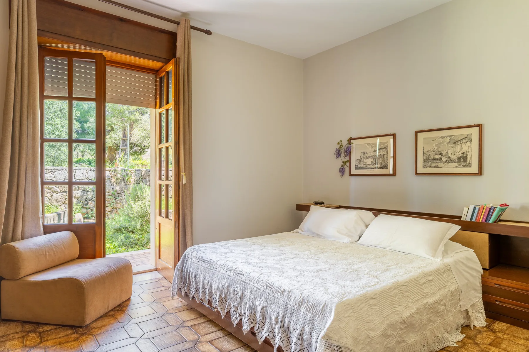 A bedroom with a bed, a cushioned seat, and an open window.