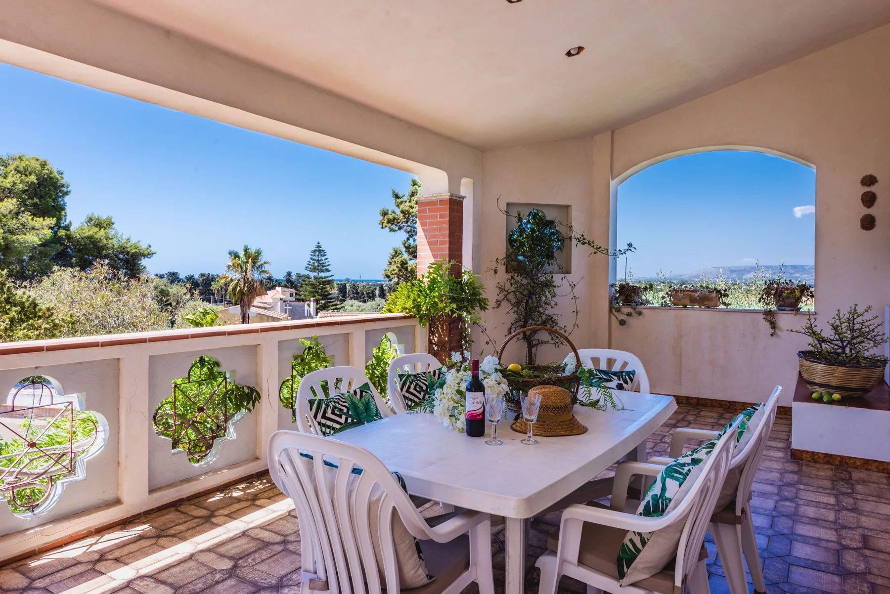 A covered outdoor dining area with a table, chairs, and views of the surrounding landscape.