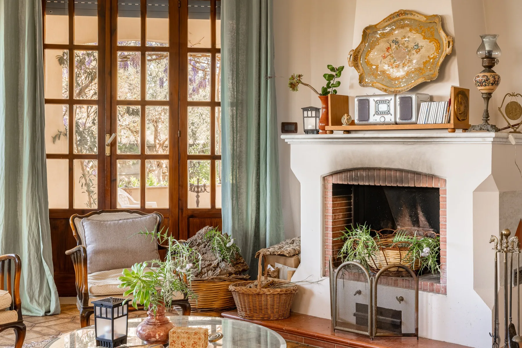A bright living room with a fireplace, tall windows, and plants.