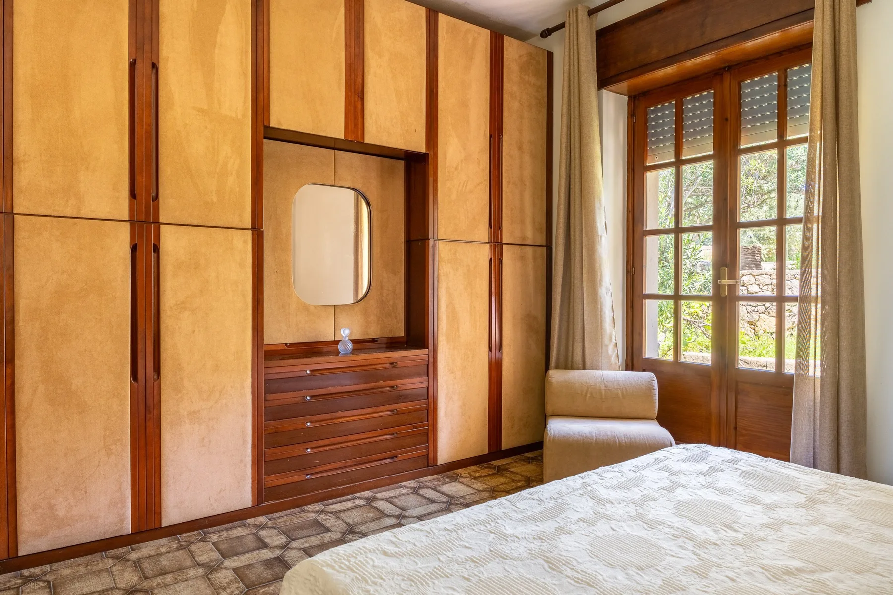 A bedroom with built-in wooden cabinetry, a window, and a bed.