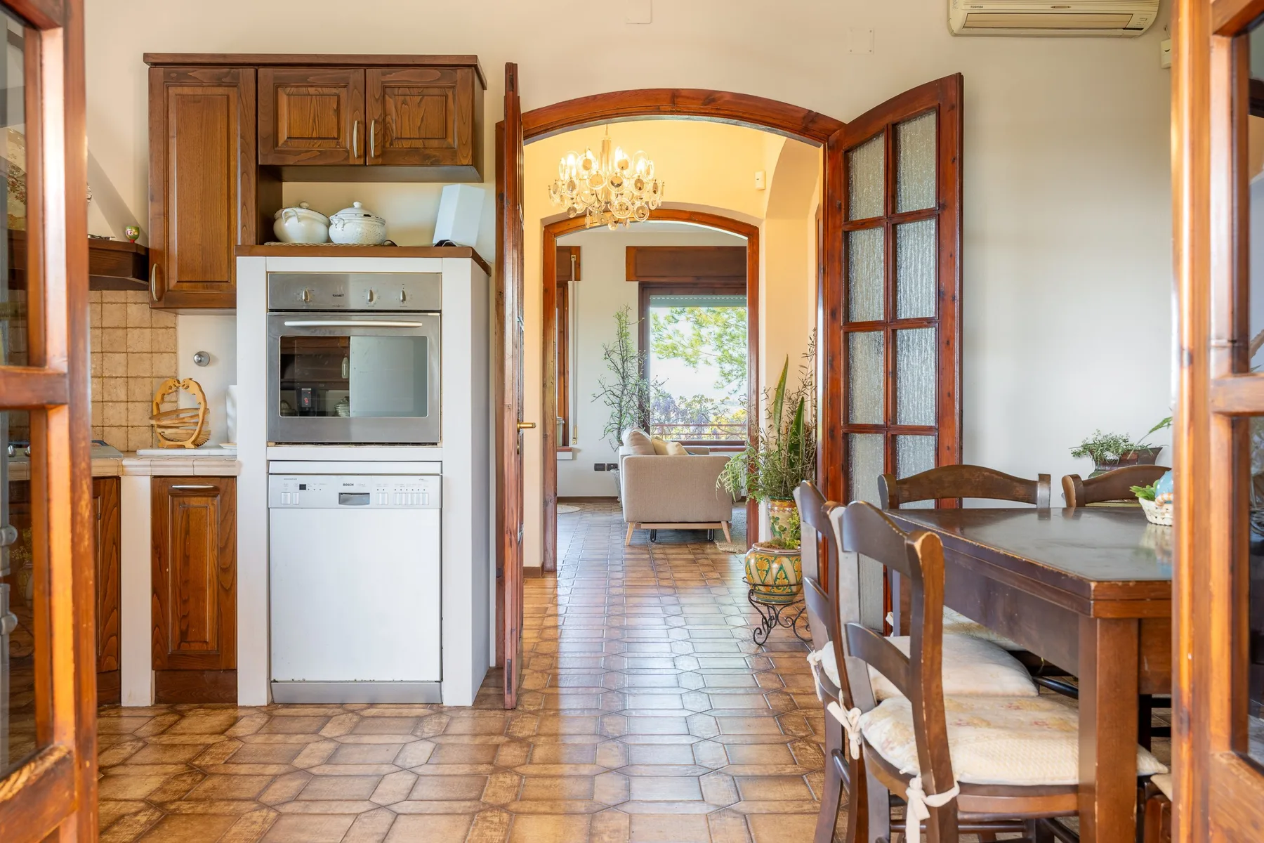 A dining area opens through an arched doorway to a sitting room, with a tiled floor.