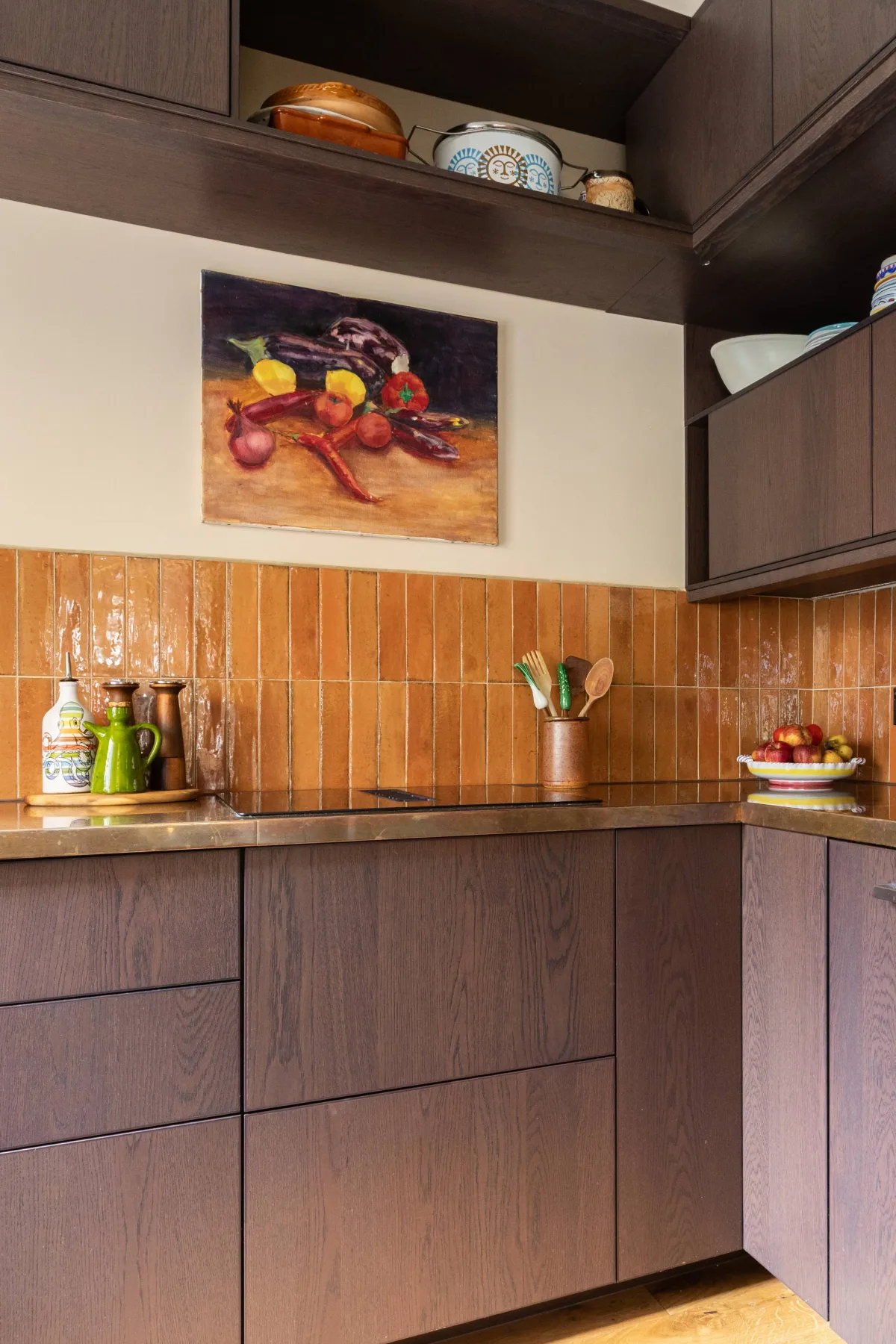 A kitchen with dark cabinetry, a countertop, and a still-life painting.