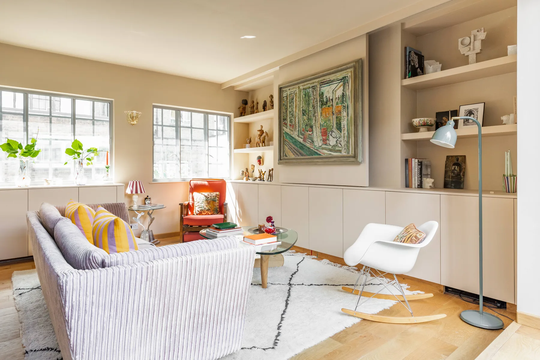 A bright living room with seating, built-in shelves, and large windows.