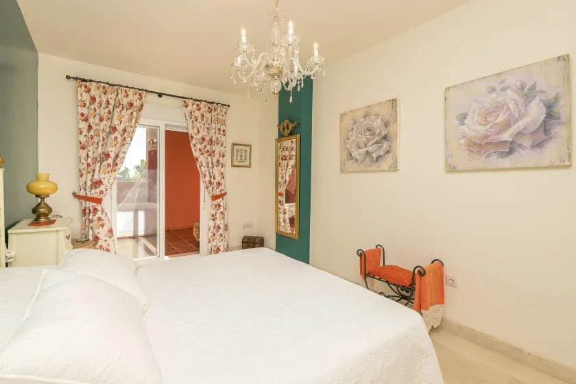 A bedroom with a large bed, floral curtains, and framed artwork.