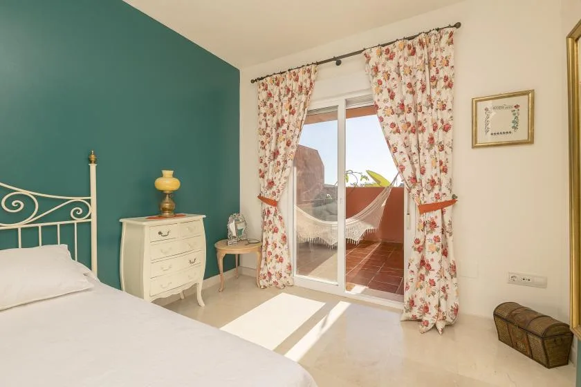 A bright bedroom opens onto a terrace through sliding glass doors.