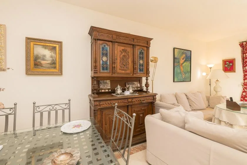 A living room with cream seating and a large wooden cabinet.
