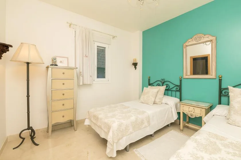 A bedroom with two beds and a turquoise accent wall.