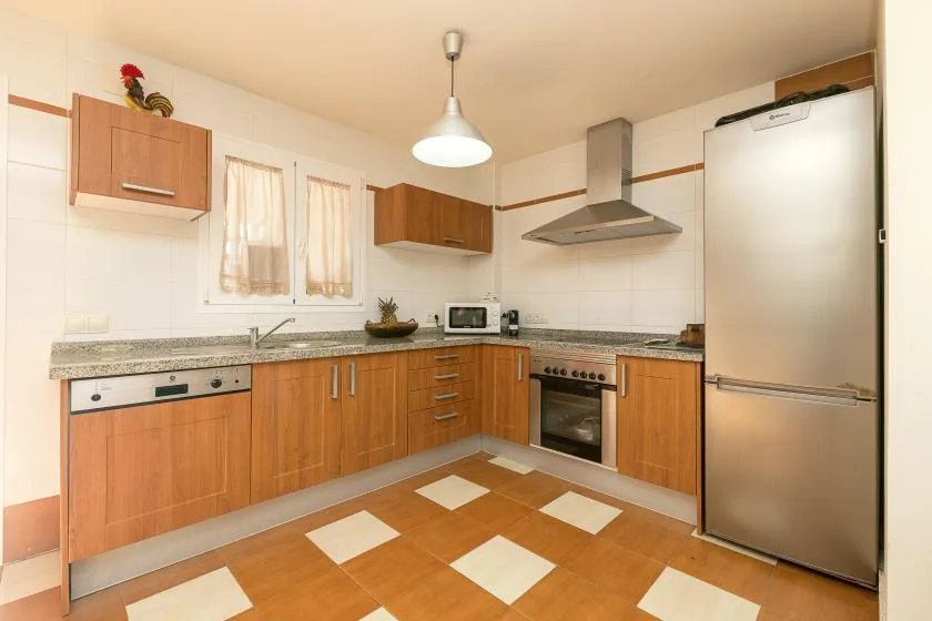 A kitchen with wooden cabinets, a countertop, and a refrigerator.