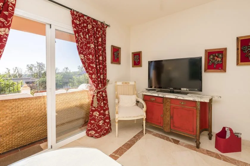 A bright living area with a television and sliding glass doors opening onto a balcony.