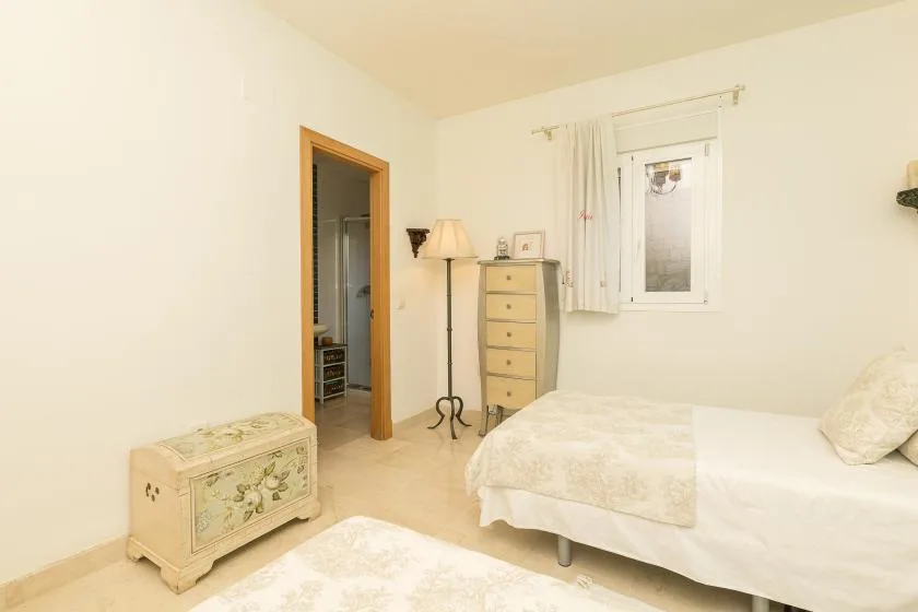 A bedroom with a bed, a chest, and a window with curtains.
