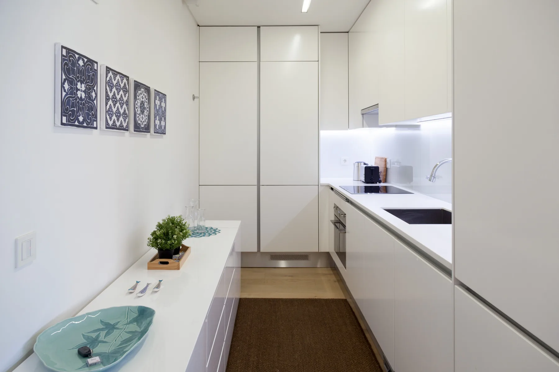 Una cocina moderna con gabinetes blancos, una encimera y una pequeña mesa de comedor.