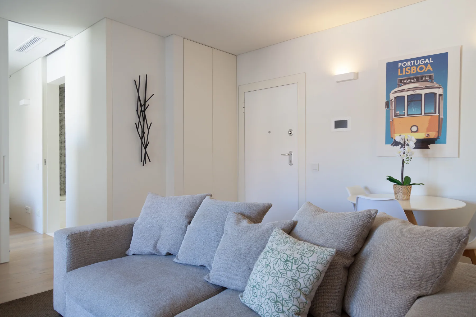 Sala de estar con una zona de asientos gris y una lámina enmarcada de un tranvía de Lisboa.