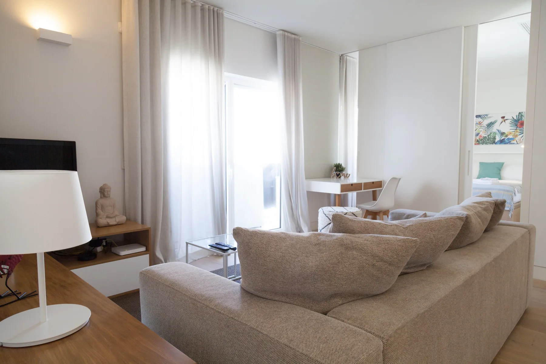 Un salón luminoso con asientos beige y una mesa de comedor junto a la ventana.