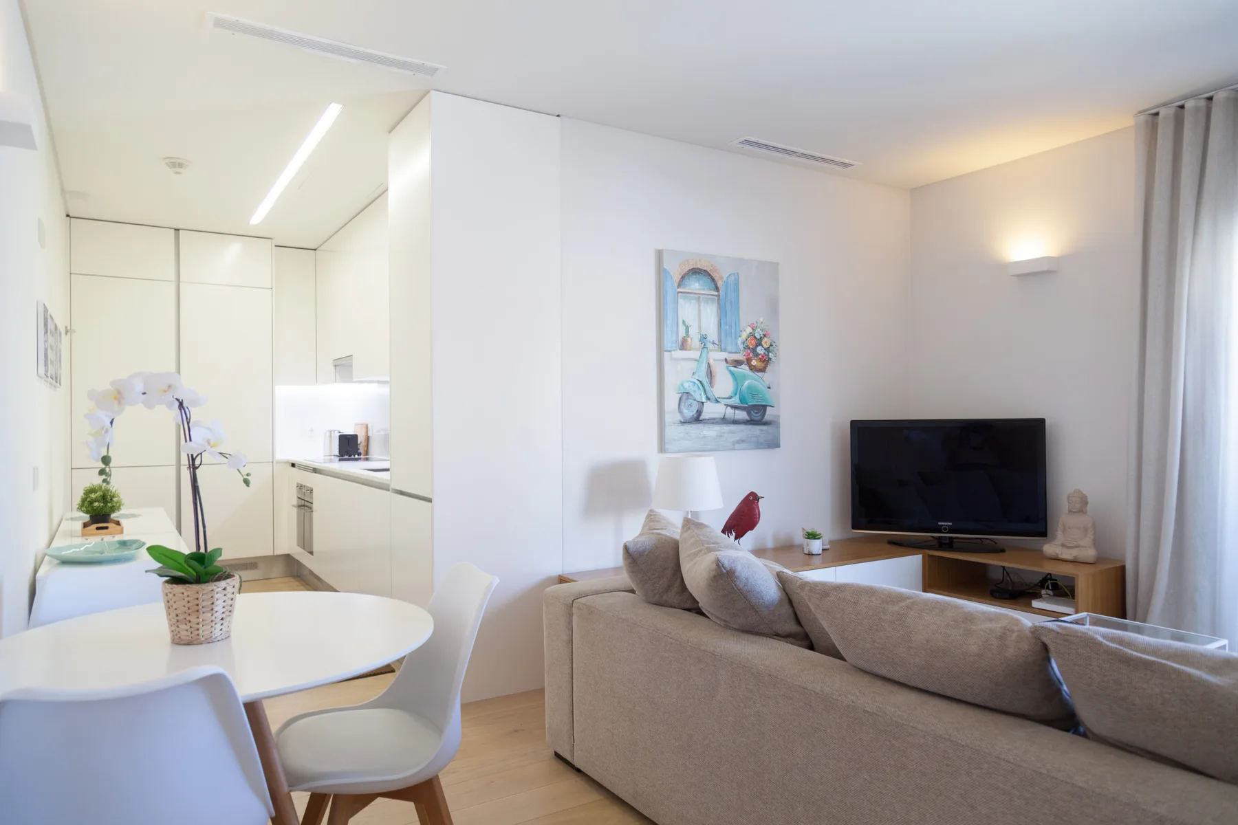 Una luminosa sala-comedor de concepto abierto con televisor y cocina.
