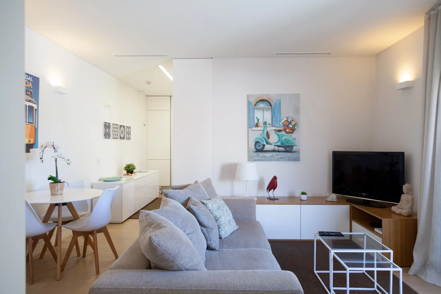 Una sala luminosa con asientos, un televisor y un comedor.