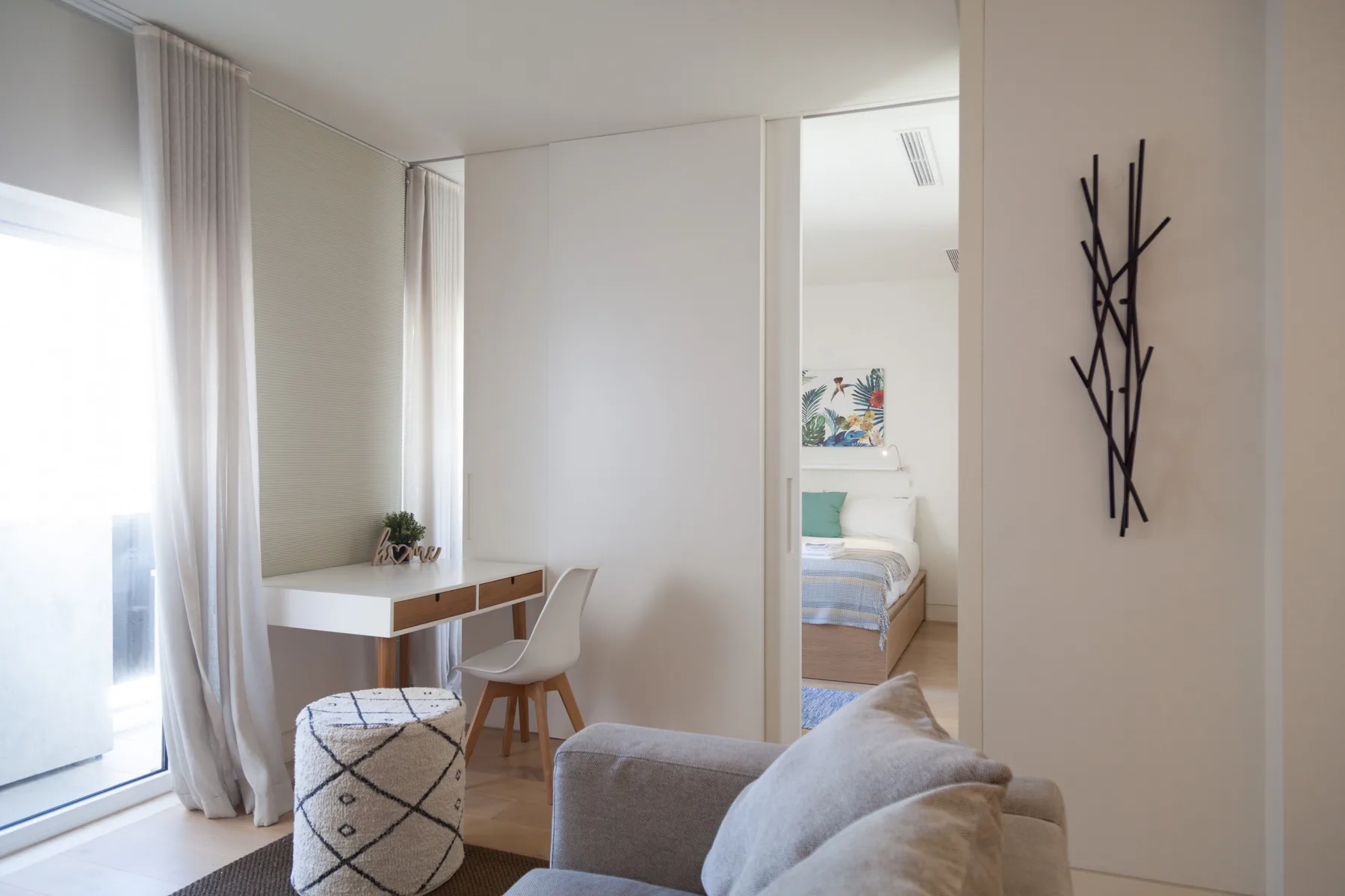 Un dormitorio luminoso con escritorio, asientos y una vista hacia la zona de descanso.