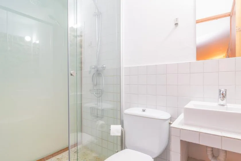 A bright bathroom with a glass shower, toilet, and sink.