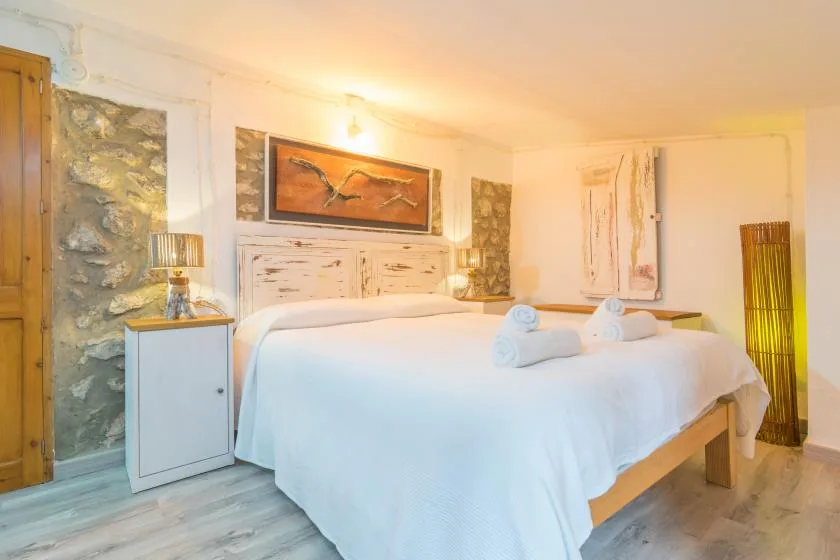 A bedroom with a large bed, folded towels, and stone wall accents.