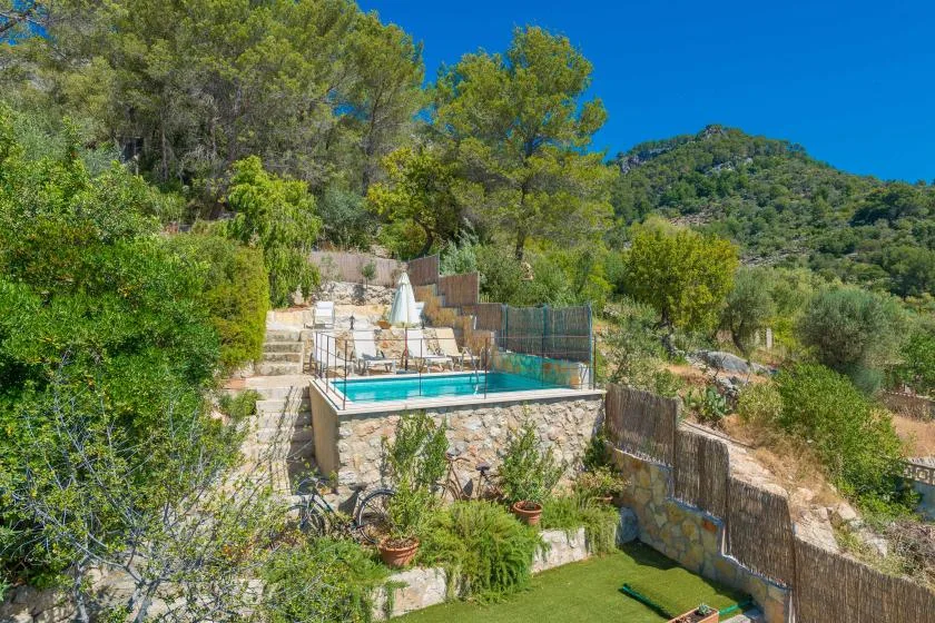 An outdoor swimming pool sits among trees and hills.