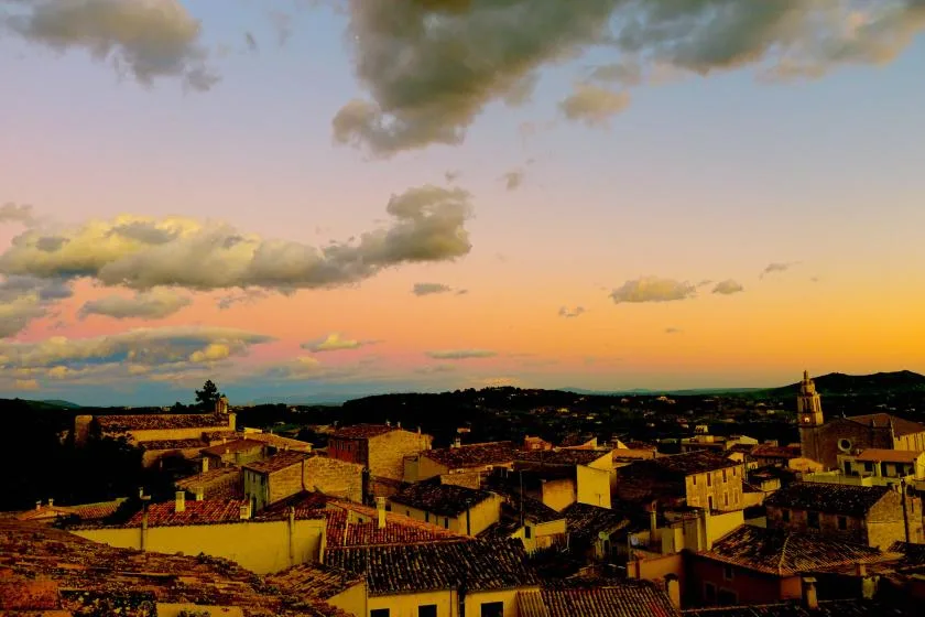 A town’s rooftops sit beneath a colorful sunset sky.