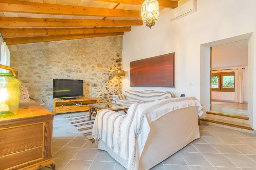 A bedroom with a bed, a television, and exposed wooden ceiling beams.
